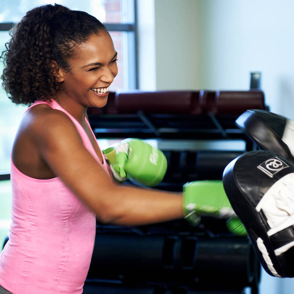 A female health club member and female personal training using boxing gloves and pads